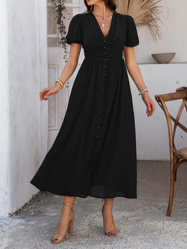 Model in black Velunira dress showcasing V-neckline and puff sleeves.