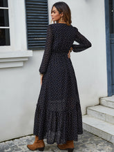  Back view of black Veyonna dress showcasing flowing silhouette, ruffled hem, and polka dot fabric.