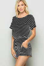 Model wearing striped romper styled with sandals and a tote, perfect for weekend brunch, beach strolls, or casual outings in warm weather.