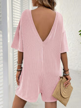 Back angle of blush pink romper with plunging back detail.