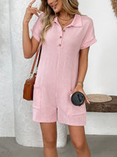 Model posing in blush pink romper against white background, front view.