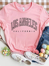 CaliVista Tee in blush pink paired with jeans and white sneakers in flat lay, styled for casual summer outfit inspiration.
