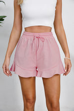 Model styled in blush pink Plus Size Drawstring Ruffle Hem Shorts, emphasizing soft feminine charm.