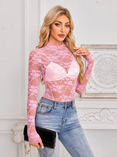 Model styled in a blush pink Mock Neck Lace Sheer Top with a sleek skirt and heels, perfect for a romantic dinner or evening out.