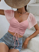 Close-up of adjustable front-center drawstring on Glowflutter Crop Top in blush pink, highlighting stretch fabric and ruching.