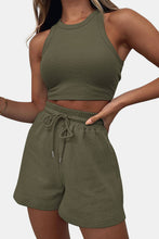 a model showcasing the Boundary Babe dark green Round Neck Top and Drawstring Shorts Set lounging in a chair at the beach.