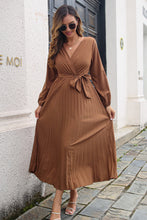 Model styled in Brown Zeleviane Pleated Maxi Dress featuring a V-neck wrap bodice, waist tie, and luxe pleats.