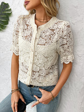 Side profile of model in a cream lace shirt with wavy ruffle sleeves, styled with sleek hair, statement earrings, and tailored pants.