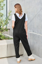 Back view of Black Caeloura Jumpsuit against mansion garden setting.