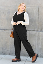 Black Caeloura Jumpsuit worn while gazing over mansion balcony beside tall pine tree.