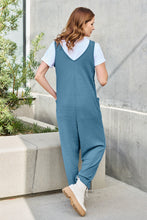 Back view of model in Sky Blue Caeloura Jumpsuit, captured against a lush resort backdrop.