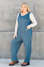 Hand slipped into pocket of Sky Blue Caeloura Jumpsuit, emphasizing functionality.