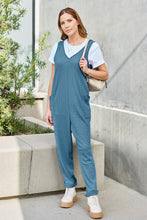Model seated in Sky Blue Caeloura Jumpsuit on resort chair, casual and polished.