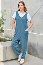 Sunset glow highlighting Sky Blue Caeloura Jumpsuit against pine tree silhouettes.
