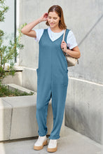 Model walking gracefully along garden path in Sky Blue Caeloura Jumpsuit.