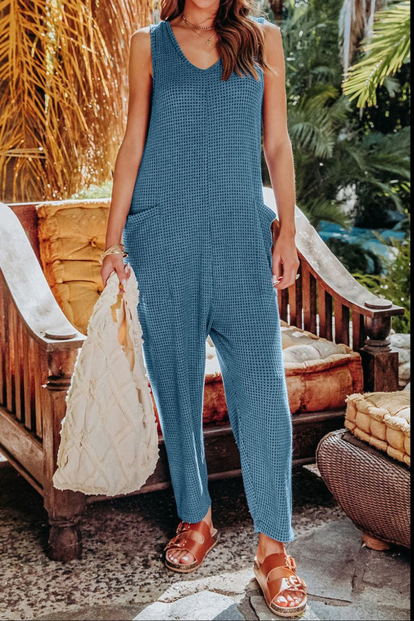 Walking through palm-lined path in Sky Blue Caeloura Jumpsuit, styled with brown buckle sandals.