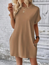 Model walking through a street fair in Camel Rahluna Mini Tee Dress styled with flat sandals and sunglasses.
