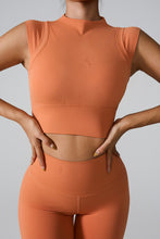 Woman wearing caramel mock neck active tank top doing aerobics.