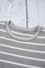 Close-up of light gray soft striped knit fabric and round neckline detail on short sleeve top, highlighting texture and quality.