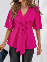 Close-up of tied front bow detail and textured fabric of the hot pink peplum blouse, emphasizing quality craftsmanship and elegant design.