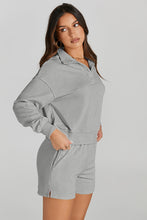 Woman wearing a cloudy blue Half-Button Sweatshirt and Shorts Active Set showcasing pocket detail.