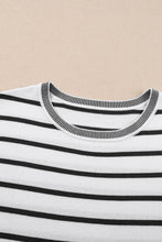 Close-up of white soft striped knit fabric and round neckline detail on short sleeve top, highlighting texture and quality.