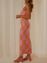 Side view of a model wearing the Coral Luxnometry Maxi Sweater Dress, highlighting its angular pattern and elegant drape inside a grand mansion hallway.