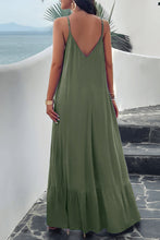 A model showcasing the back of a matcha green Backless Maxi Cami Dress with Pockets paired with jewelry and clear heels posing on an Oceanview balcony 