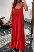 a model posing on a balcony wearing a deep red Backless Maxi Cami Dress with Pockets  paired with jewelry, a woven handbag, and clear heels