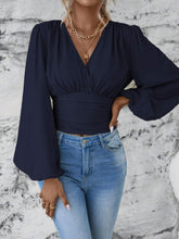 Front view of the dark blue Balloonique™ Blouse highlighting smocked neckline and balloon sleeves, paired with light blue washed jeans, and jewelry.