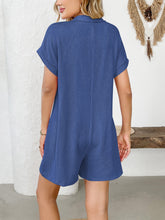 Back shot of romper in dark blue on model with flowing hair.