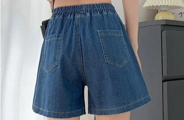 Back view of plus size dark blue spliced ruffle hem denim shorts with pockets.