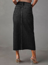 Back view of dark Denvara Raw Hem Front Slit Denim Midi Skirt showcasing back pockets and raw hem