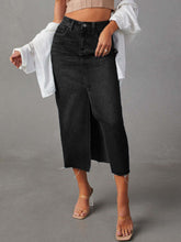 Front view of black Denvara Raw Hem Front Slit Denim Midi Skirt styled with a dusty pink crop top layered with white button-down and clear heels
