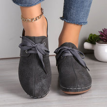 A model showcasing the front of a pair of the dark grey Lace-Up Round Toe Wedge Sandals and a gold anklet and blue jeans.