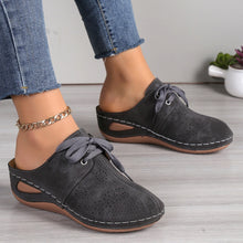 A model showcasing the sides of a pair of the dark grey Lace-Up Round Toe Wedge Sandals and a gold anklet and blue jeans.