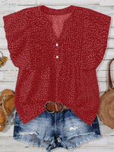 Front view of EverDot Flutter Top in deep red polka dot with flutter sleeves paired with earrings, belt, brown sandals, and straw handbag in a flat lay photo.