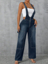 Side profile of Denivelle™ Denim Overalls showing plunging V-neck zip and adjustable straps in medium blue.