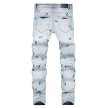 Back view of light blue skinny-leg denim jeans with light blue dice, letter embroideries, and washed finish.