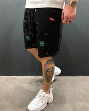 Side walking view of black embroidered Bermuda shorts styled casually.