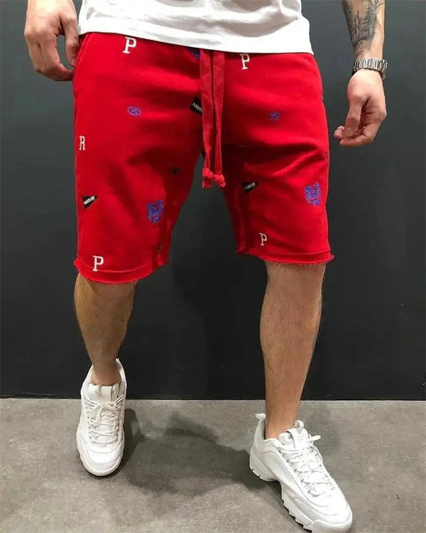 Side walking view of men’s red Bermuda shorts with bold embroidery.