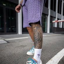 Close-up of darl violet Draynoir shorts styled with sneakers highlighting texture and fit.