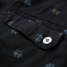 Back pocket flap button detail on black Bermuda shorts.