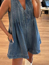Close-up on dusty blue romper's tie string and fine-textured pleats—faded elegance meets casual ease in this soft-washed denim finish.