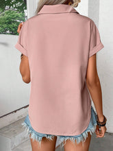 Back view of model showcasing the lightweight, relaxed fit of the dusty pink pleated collared neck short sleeve blouse, paired with white trousers.
