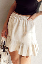 Close-up Front view of beige Elunari Ruffled Hem Mini Skirt styled with a black cropped blouse