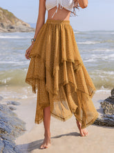 Elurevyn gold polka dot print lace midi skirt styled with casual white top, standing barefoot on island sand