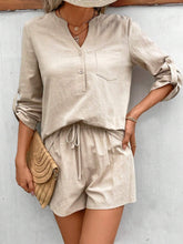 Model wearing sand Everyday Escape Lounge Set standing with a straw hat and straw handbag on a sunny day.