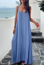 a model posing on a balcony wearing a sky blue Backless Maxi Cami Dress with Pockets  paired with jewelry, and clear heels