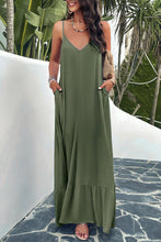 a model posing on a balcony wearing a matcha green Backless Maxi Cami Dress with Pockets  paired with jewelry, a woven handbag, and clear heels